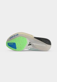 Semelle d’une chaussure de course montrant une adhérence Continental verte et bleue, un motif de talon noir, et le texte « FOLLOW THE LINE » en bleu sur une semelle beige.