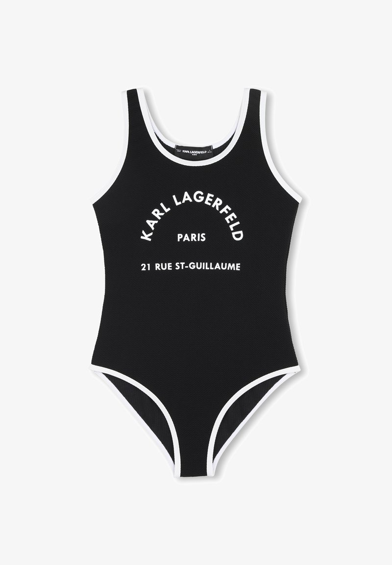 Maillot de bain une pièce noir avec bordures blanches, texture côtelée, et texte frontal indiquant "KARL LAGERFELD PARIS 21 RUE ST-GUILLAUME."