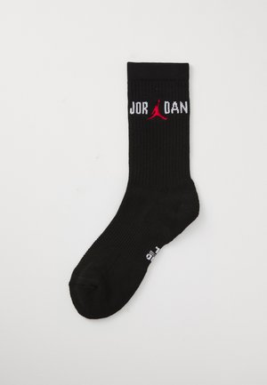 Sort mid-calf strømpe med hvid "JORDAN" tekst delt af rødt Jumpman-logo på manchet, ribbet tekstur, samt "FLY" tekst på siden nær sålen.