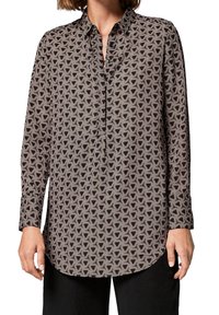 Chemise à manches longues avec un motif géométrique hexagonal en marron et crème. Fabriquée en tissu lisse avec un col à revers et une patte de boutonnage.