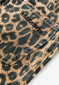 Tela de leopardo en tonos beige y verde oscuro, con costuras visibles y un pequeño detalle de logo. El material tiene un acabado texturizado.