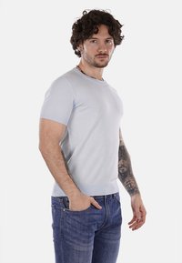 Maglietta a maniche corte di colore azzurro chiaro in maglia, con scollatura rotonda e orlo a coste, abbinata a jeans blu scuro. Presenta una vestibilità comoda e una texture liscia.