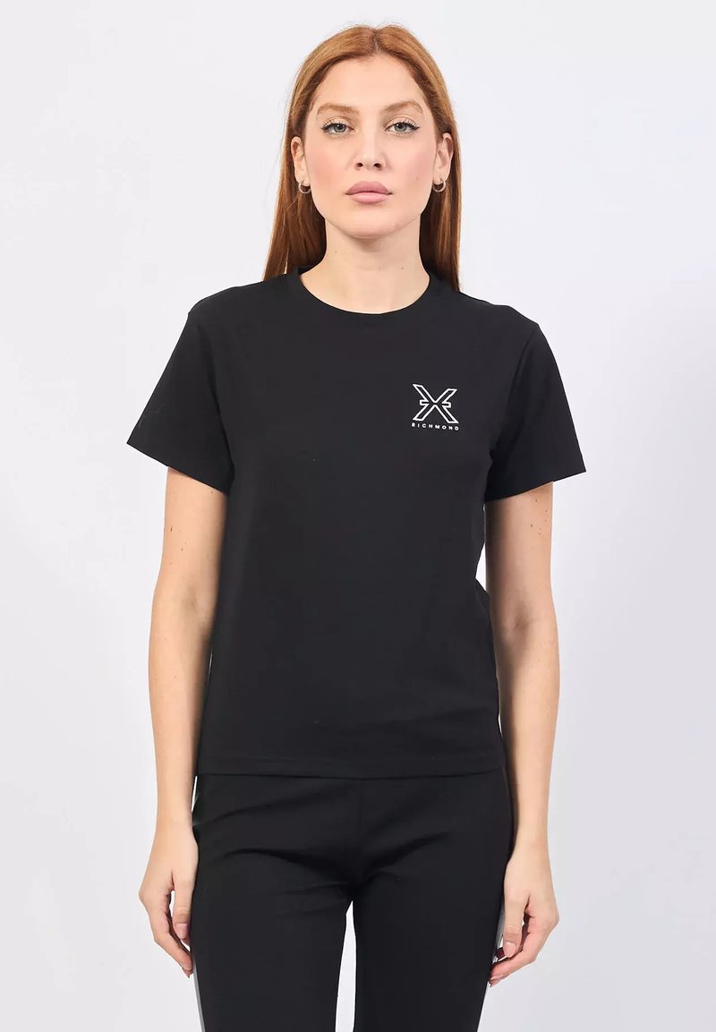 Maglietta in cotone nera con maniche corte, scollatura rotonda e logo a sinistra sul davanti che presenta una "X" stilizzata in bianco. Tessuto liscio, design aderente.