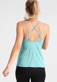 Débardeur de sport bleu sarcelle clair avec un tissu texturé, doté de bretelles croisées dans le dos et d'une coupe décontractée.