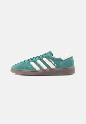 Green suede sneaker with white leather accents and three white stripes. Features a rubber sole and padded collar for comfort.