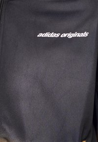 Čierna zipsová bunda z hladkej tkaniny s bielym logom "adidas originals" na ľavej hrudi.