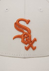 Baseballcap aus leicht beigem Stoff mit einem orangenen, gestickten "Sox"-Logo. Verfügt über ein strukturiertes Design und Belüftungsöffnungen.