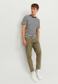 Gestreiftes Kurzarmhemd in Marineblau und Weiß, kombiniert mit olivgrünen Hosen und weißen Sneakers, mit klassischer Passform und lässigem Design.