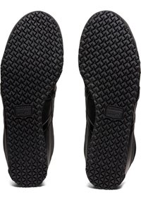 Black shoe soles with a textured diamond pattern for traction, featuring a smooth upper edge and a label on the heel area.