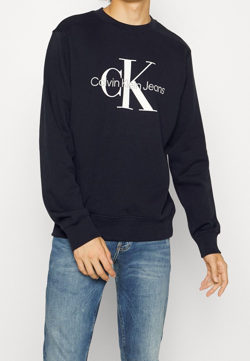 Svart sweatshirt med vit "Calvin Klein Jeans"-logotyp. Har en klassisk rund halsringning, långa ärmar, ribbad mudd och nederkant. Mjuk textur.
