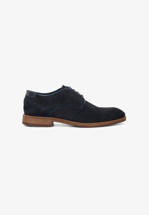 Navy suede oxford shoe with lace-up design, rounded toe, and contrasting tan rubber sole. Features textured heel and smooth upper.