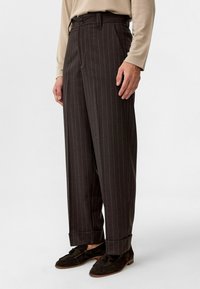 Bruine pinstriped broek met een hoge taille, geplooide voorkant en een wijd pootontwerp, met twee knopen op de tailleband en een lichte omslag.