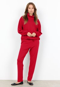 Red sweatshirt with a high collar and elastic cuffs, paired with matching red sweatpants featuring a drawstring. Simple design, smooth texture.