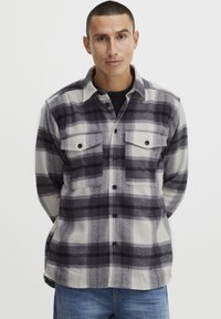 Geruite flanellen shirt in zwart, grijs en wit, met knoopsluiting aan de voorkant, twee borstzakken en een klassieke kraag. Zachte, gemergelde stof.