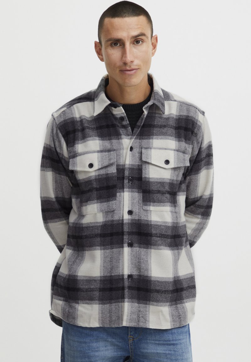 Geruite flanellen shirt in zwart, grijs en wit, met knoopsluiting aan de voorkant, twee borstzakken en een klassieke kraag. Zachte, gemergelde stof.