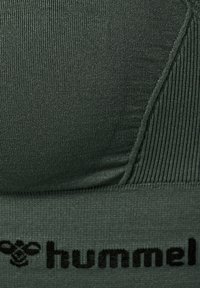 Groene sportbeha met een geribbelde textuur, een elastische band met "hummel"-branding en een gladde stof met een aansluitend ontwerp.