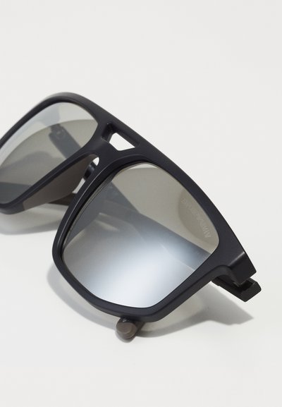 Ochelari de soare rectangulari negri cu lentile gri reflective și un finisaj mat. Au o ramă geometrică și accente metalice la sprijin.
