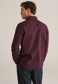 Bordo ilgos rankovės marškiniai su klasikiniu apykakle, lygiu paviršiumi ir apvaliu hemu. Su sagomis užsegamomis rankovėmis ir pritaikytu siluetu.