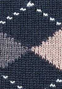 Strickstoff mit dunkelblauem Hintergrund und geometrischen Formen in Hellrosa, Grau und Weiß. Sanfte Textur mit glattem Garn.