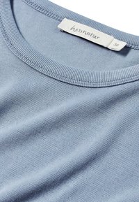 Ljusblå bomulls t-shirt med rund halsringning och ribbad krage, med en etikett som visar "hessnatur" och storlek "36" broderat på insidan.