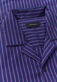 Laivastonsininen ja violetti raidallinen paita, jossa on lovettu kaulus, nappilukko ja "Matinique" -labeli. Sileä pinta, kevyt kangas.