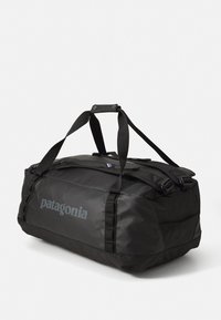 Black Patagonia duffel bag with dual carrying straps and shoulder straps, shown on a plain white background.