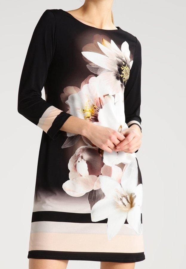 Czarna sukienka z rękawami o długości trzech ćwiartek, zdobiona dużymi białymi i różowymi kwiatowymi nadrukami oraz poziomymi paskami w odcieniach beżu i czerni na dole.