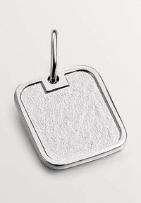 Colgante de metal plateado, forma rectangular con una superficie texturizada. Los bordes son suaves y pulidos. Incluye un lazo para su sujeción.