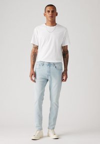 Hvit bomulls T-skjorte, lyseblå denim jeans og hvite joggesko. Rett passform med minimal slitasje. Enkelt, klassisk design.