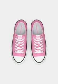 Ροζ καμβά αθλητικά παπούτσια με άσπρα κορδόνια και άσπρη μύτη. Μαύρη λαστιχένια σόλα, λογότυπο στη γλώσσα και στις πλευρές, λεία υφή, casual σχεδιασμός.