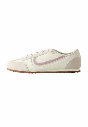 Low-profile beige sneaker with white laces, suede toe and heel, and a wavy pink stripe detail on the side.