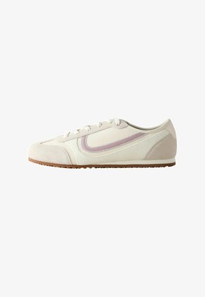 Low-profile beige sneaker with white laces, suede toe and heel, and a wavy pink stripe detail on the side.