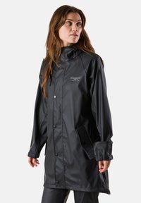 Schwarzer wasserdichter Regenmantel mit hohem Kragen, vorderem Druckknopfverschluss, verstellbaren Kordeln und seitlichen Taschen. Logo auf der Brust angezeigt.
