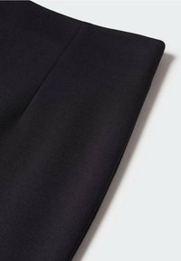 Schwarzes Textilprodukt mit glatter Textur, das ein sauberes, maßgeschneidertes Design und eine scharfe, gefaltete Kante aufweist.