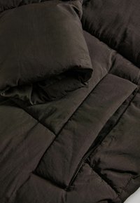 Couverture en duvet matelassée noire et housse d'oreiller, fabriquées en tissu doux, présentant une texture lisse et des lignes épurées sans motifs ni éléments visibles.