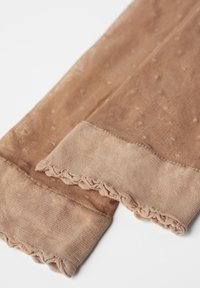 Brune strømpebukser med prikket tekstur, ribbede ankelmanchetter og bølget kant. Fremstillet af et let, blødt materiale for komfort.