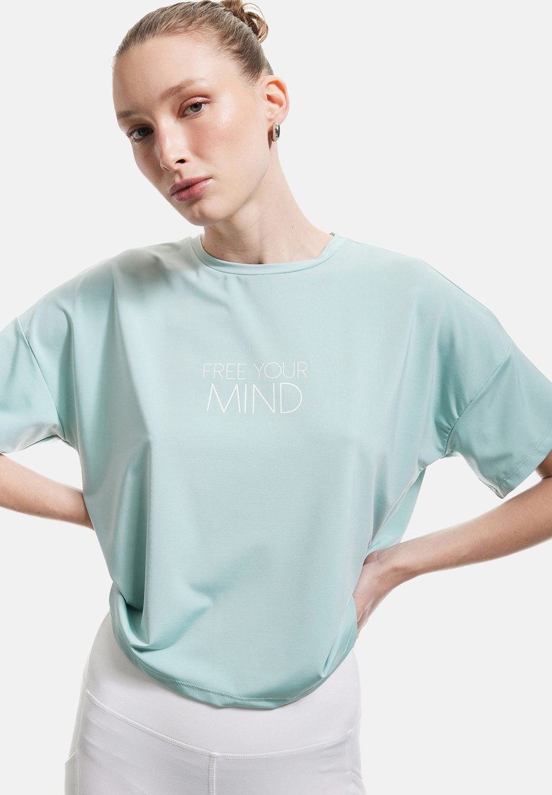 Camiseta atlética de manga corta en azul claro, fabricada con tejido que absorbe la humedad, con el texto "LIBERA TU MENTE" en blanco centrado en el frente.