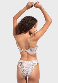 Bra and high-waisted bikini in light purple with leopard print, featuring gold straps and accents, distinct floral and portrait patterns.