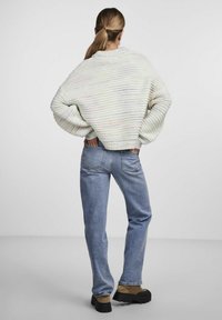 Tjock krämfärgad tröja med horisontella ränder, ribbade ärmslut och fåll. Matchad med ljusblå denimjeans och svarta platåskor.