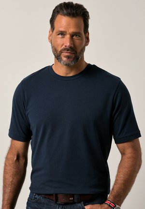 Navyblaue Kurzarm-T-Shirt aus einem glatten Stoff. Es hat einen klassischen Rundhalsausschnitt und eine lockere Passform. Wird mit dunklen Jeans und einem Gürtel getragen.