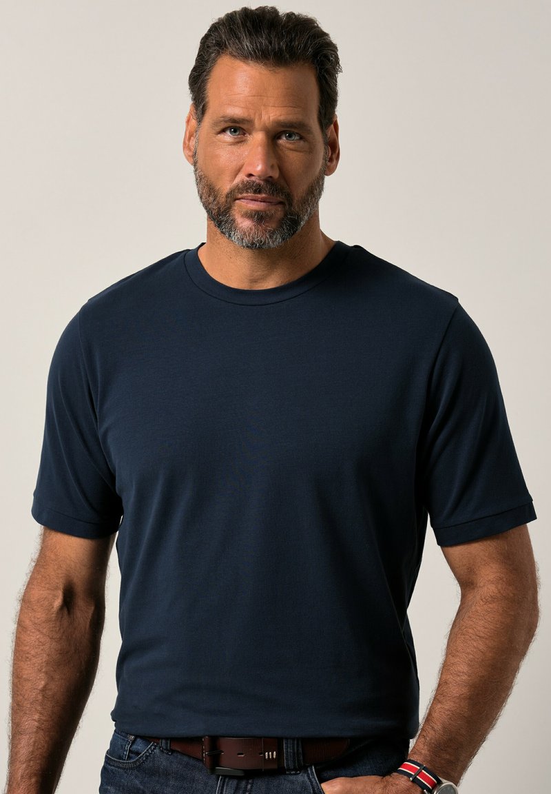 Námořnická modrá tričko s krátkým rukávem vyrobené z hladké tkaniny. Má klasický kulatý výstřih a volný střih. Nosit s tmavými džínami a opaskem.