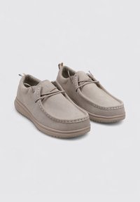 Scarpe in suede grigio chiaro con design stringato, cuciture a contrasto, punta arrotondata e suola in gomma testurizzata.