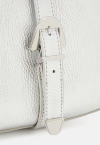 Kukku harmaata tekstiilistä valmistettu nahkaremmi, jossa on metallinen solki ja säädettävät reiät. Varustettu kiillottavalla hopeanvärisellä metalliosalla ja ompelu yksityiskohdilla.