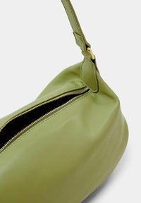 Grøn læderhåndtaske med en blød tekstur, med en guldlås og en justerbar rem. Rundet form med minimale designdetaljer.