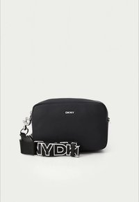 Mala tiracolo preta da DKNY com textura suave, forma retangular, ferragens prateadas e correia com logótipo branco contrastante. Design simples e funcional.