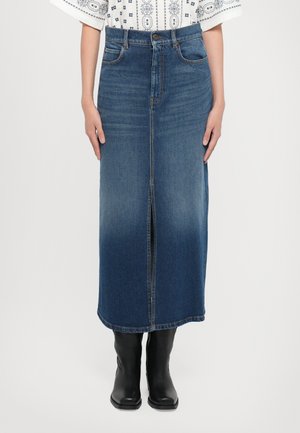 Denim skirt in medium blue, knee-length with a front slit. Features a classic waistband and five-pocket design, paired with black boots.