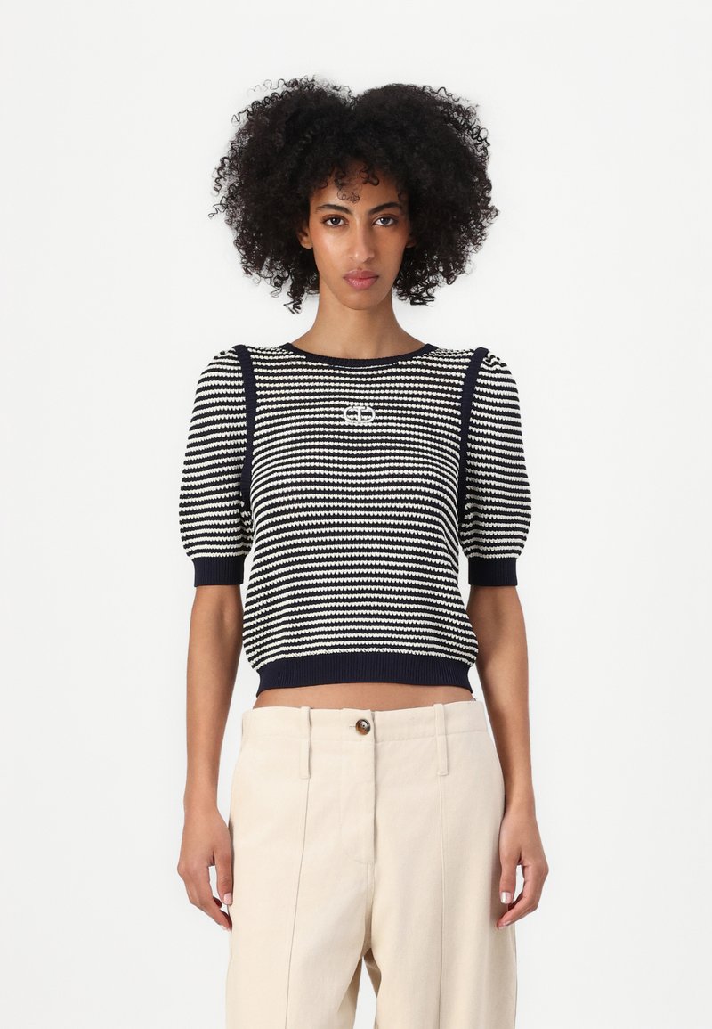 Maglione corto a righe blu navy e bianche lavorato a maglia con maniche a sbuffo e scollo rotondo. Presenta un dettaglio del logo sul davanti e orlo a coste.