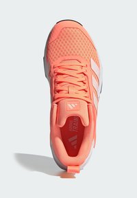 Coral training shoe with mesh upper, padded tongue, and laces. Features white accents and a flexible rubber sole for traction.