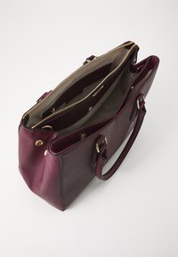 Burgundy leather handbag with gold-tone hardware, two interior compartments, and a textured exterior. Features dual handles and zip closure.