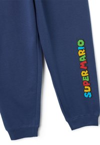 Marineblauwe joggingbroek met ribbelboorden, met een kleurraf ‘‘SUPER MARIO’’-grafiek in verschillende felle kleuren langs het linkerbeen.